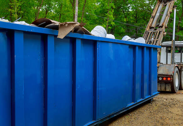 A dumpster is loaded with trash, and a truck takes the dumpster away in Danbury, Connecticut.